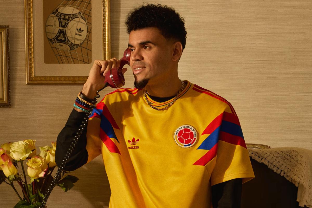 Luis Díaz usando camiseta retro amarilla de los años 90, hablando por teléfono en una escena de estilo vintage