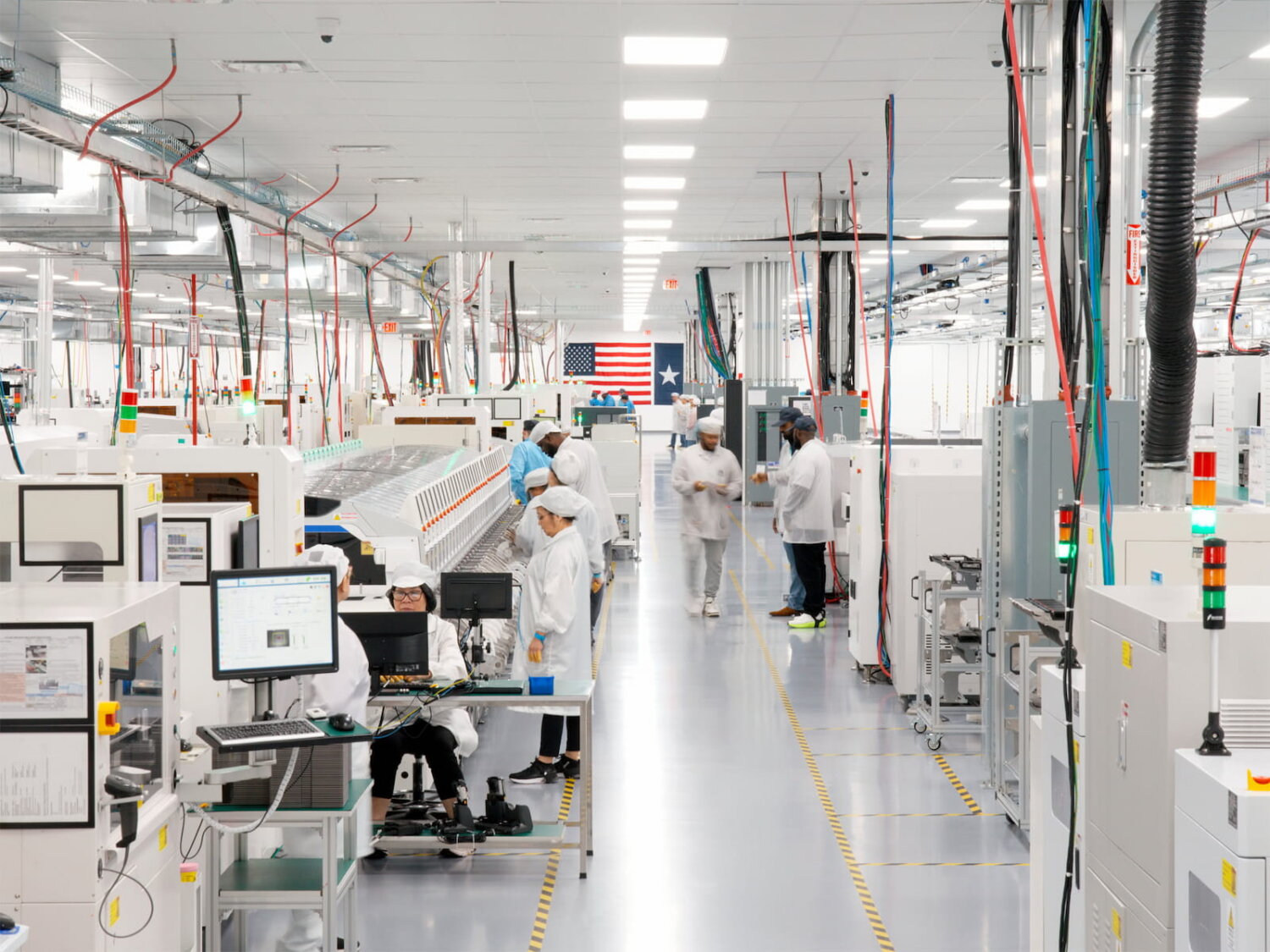 Interior de la planta en Houston donde Apple fabrica el Mac mini como parte de su estrategia de manufactura en Estados Unidos, con trabajadores en líneas de ensamblaje y maquinaria industrial bajo iluminación blanca